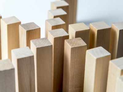 Many curved lines of wooden cubes are connected in the center into one, as a symbol of queues, a variety of tasks and a leader, on an uneven white background.